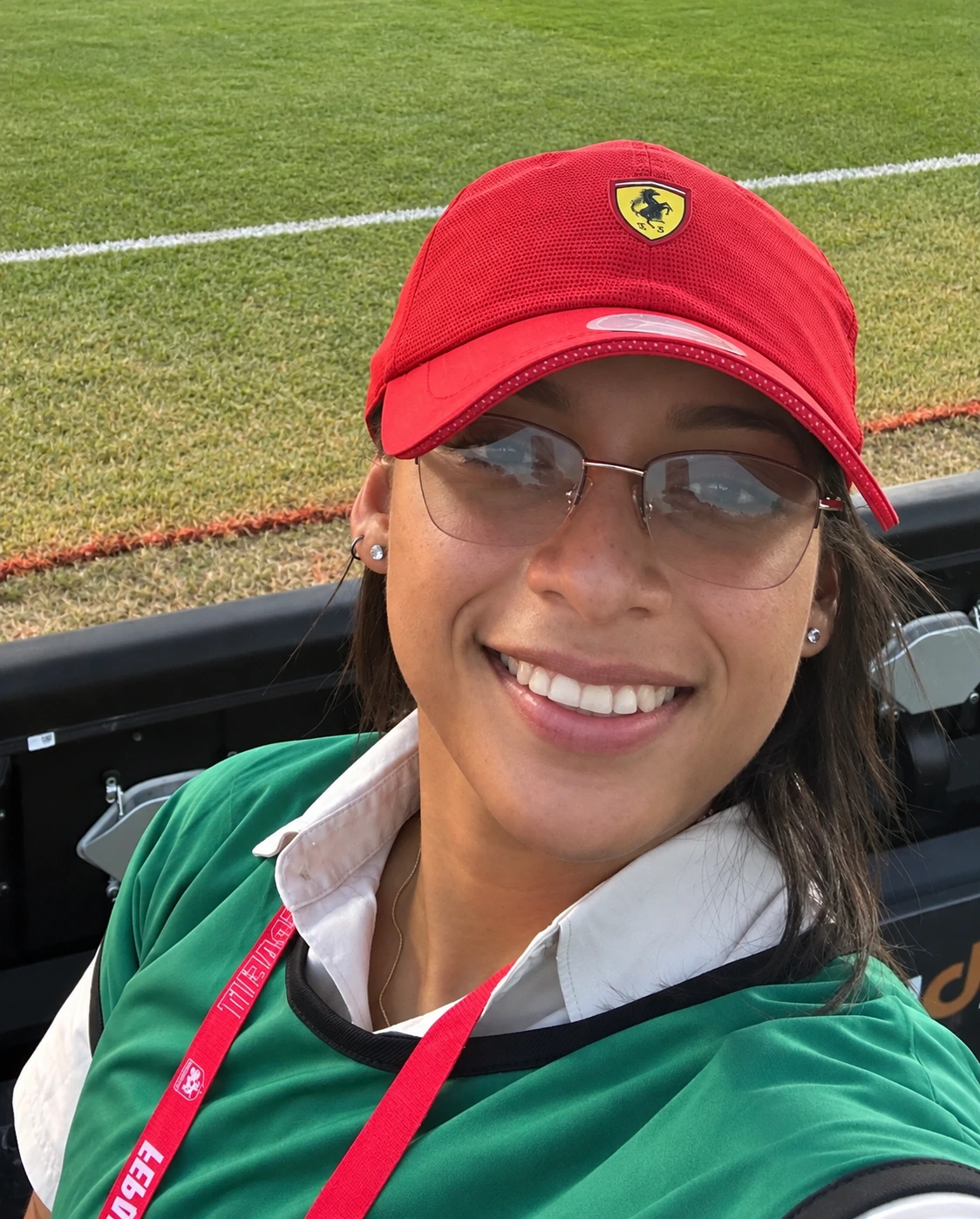 Adyanis Adames sonriendo junto a la cancha, con gorra roja y credencial