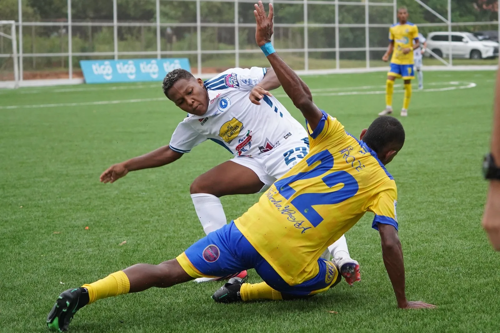 Jugador de amarillo haciendo una barrida contra un rival de blanco