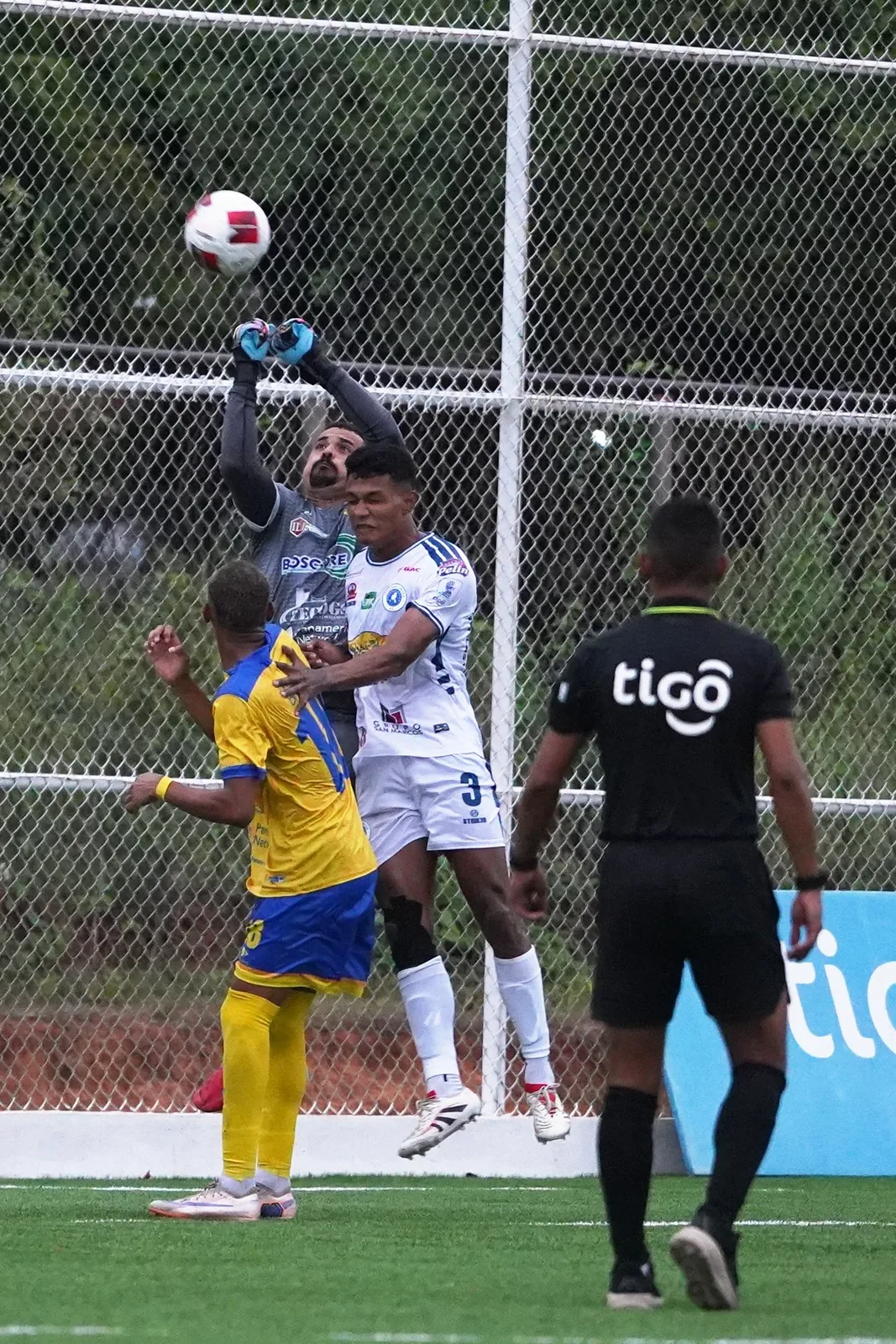 Portero despejando el balón de puños en un área llena de jugadores