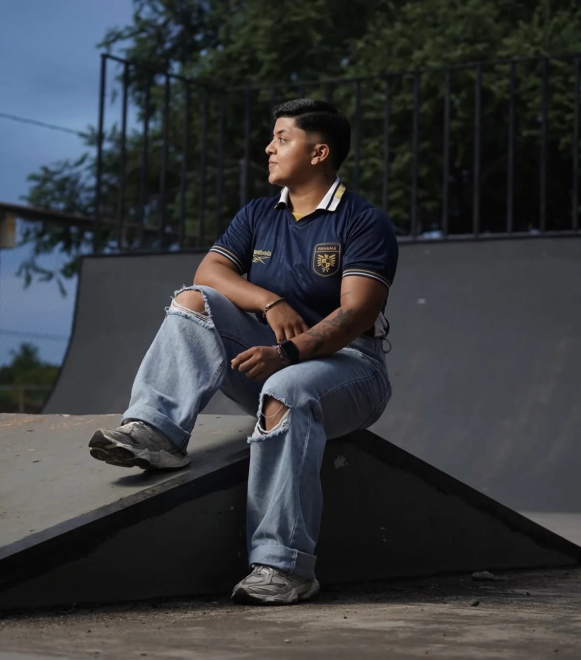 Joven con camiseta de Panamá sentado sobre una rampa de patinetas